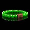 Handmade green jade beaded bracelet with vibrant green stones and a dark wood engraved 'JASE' logo block, shown on a reflective black surface.
