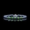 The Magnate bracelet by onejase with faceted green emerald beads, black lava stone, and hematite spacers, featuring a stainless steel clasp, on a black reflective surface.